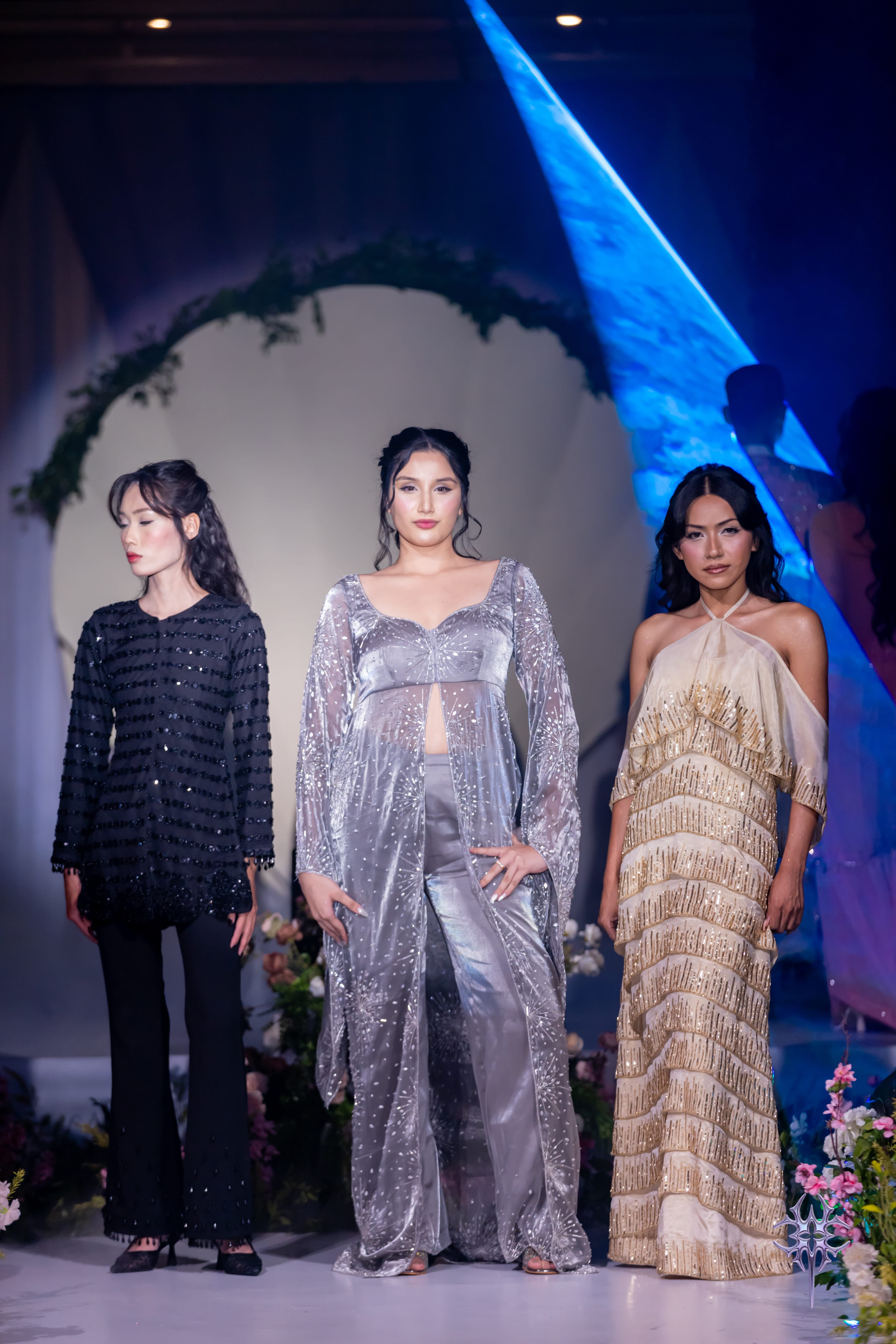 Three Asteria partywear looks on the runway — a black sequinned tunic, a silver beaded cape over trousers, and a gold tiered halter gown